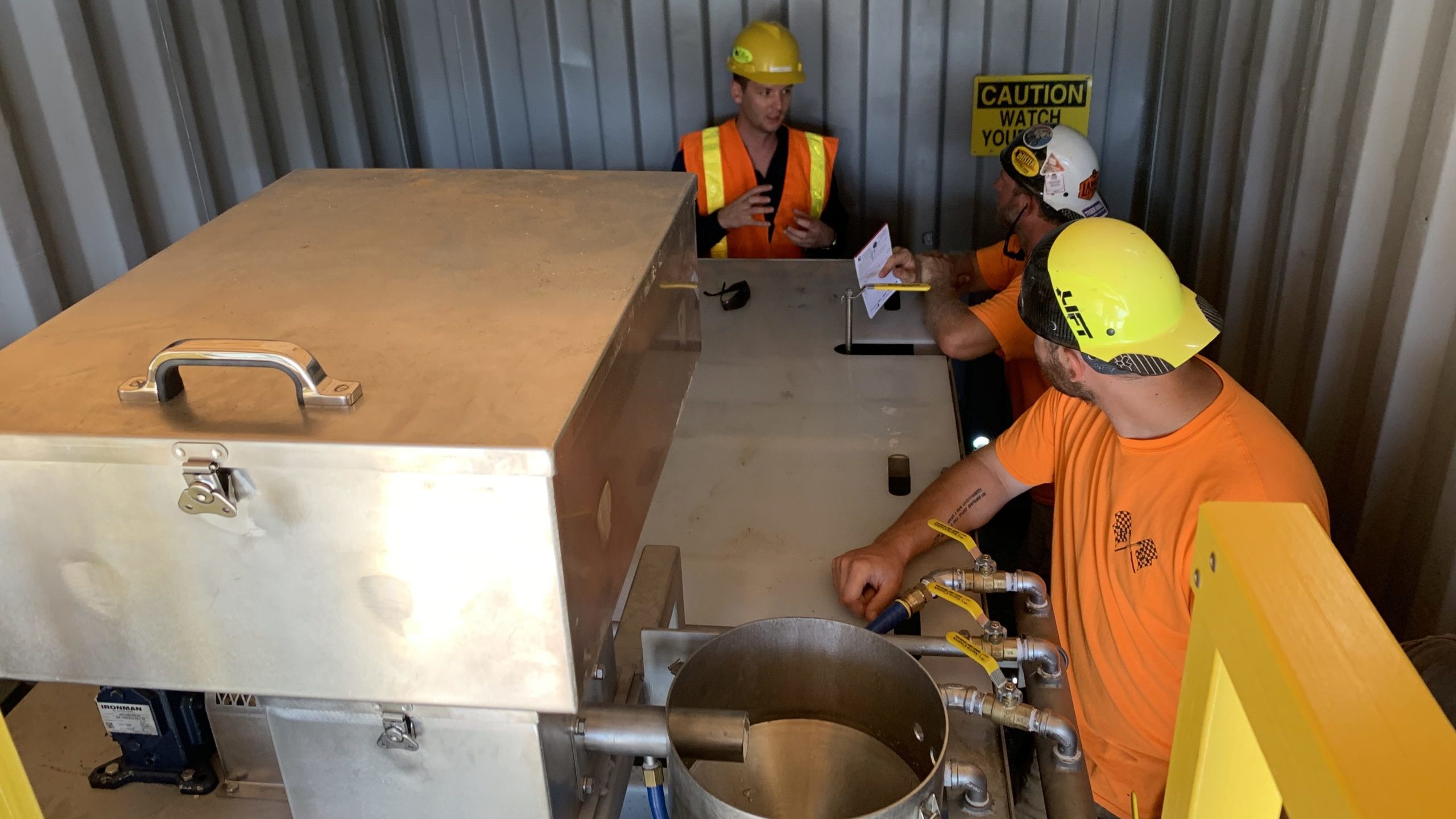 A clearwater employee is training two men how to use Clearwater's polymer batching system
