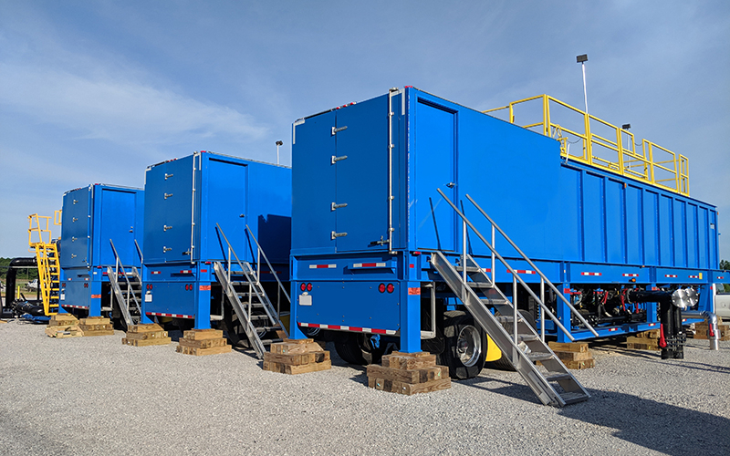 Three blue portable water clarifiers cribbed up outside at a job site.