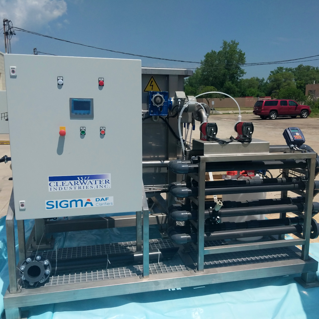 A DAF skid pictured outside with a control panel and flocculator tubes in the foreground and unidentifiable components in the background.