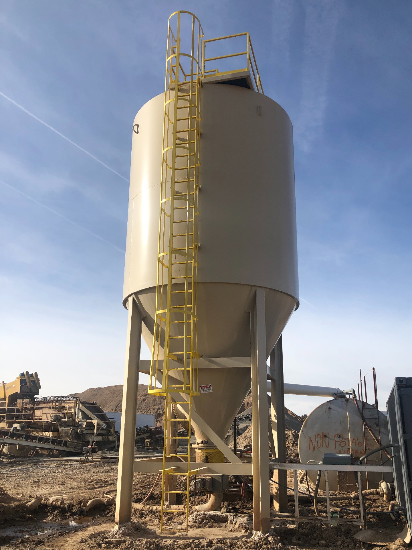 A tall slurry thickener setup at an aggregate production pit.