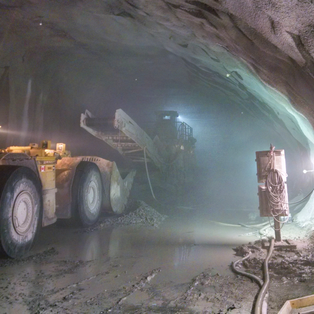 A conveyor and other industrial equipment in a dusty tunnel.