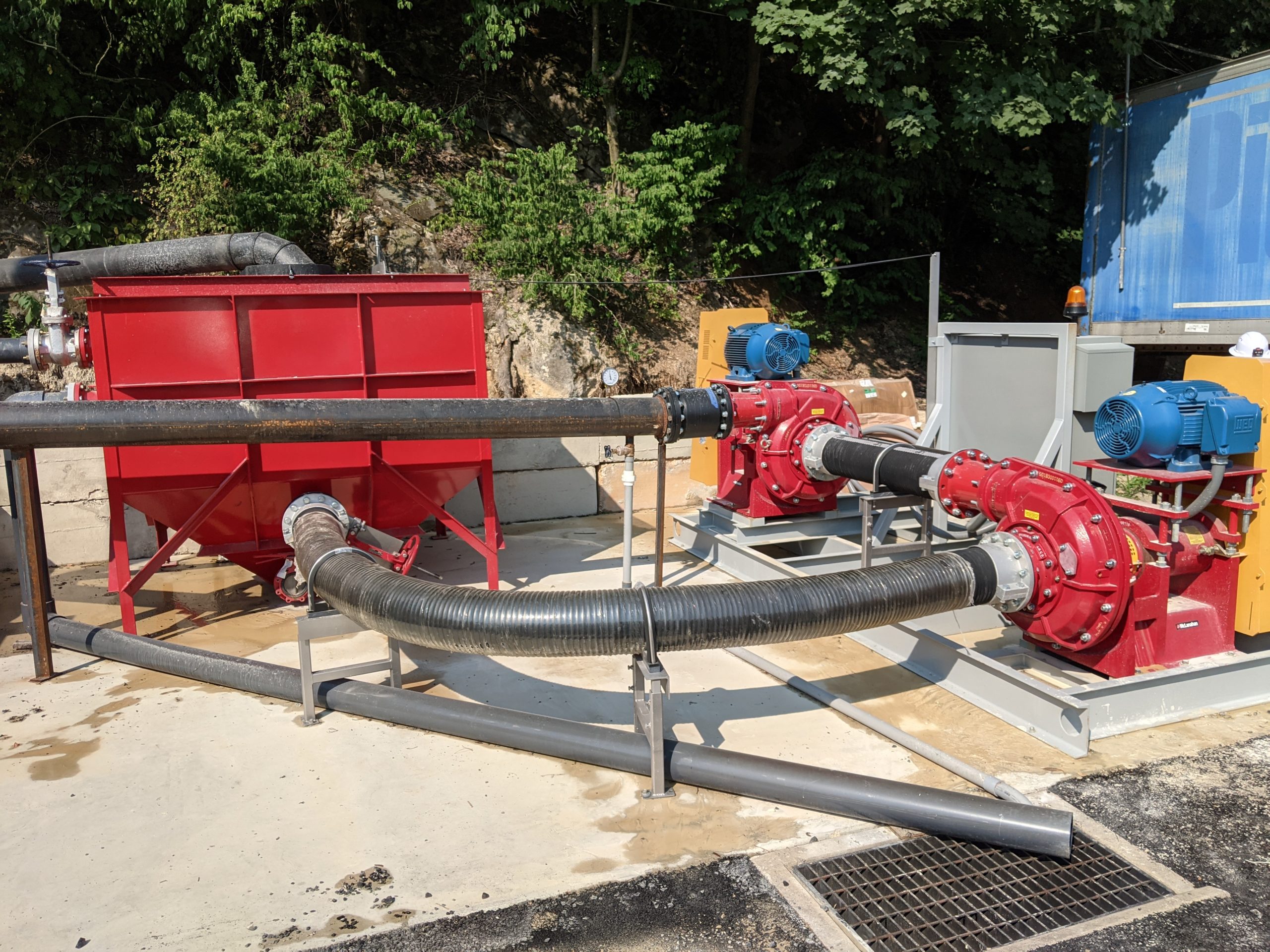 A red sump tank with two water pumps and plumbed piping.