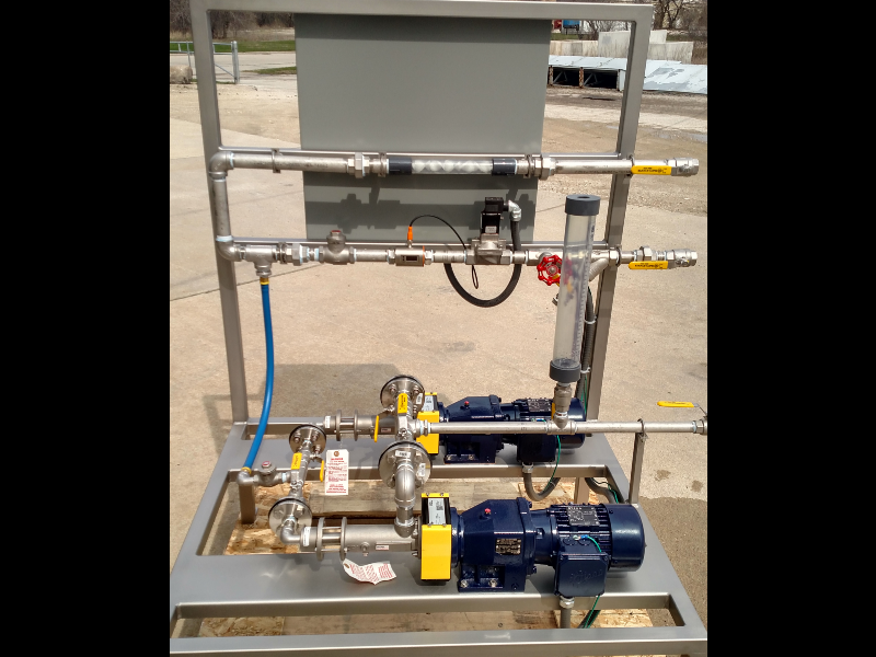 A liquid chemical feed system with two pumps, piping, static mixer, and control panel on a single skid.