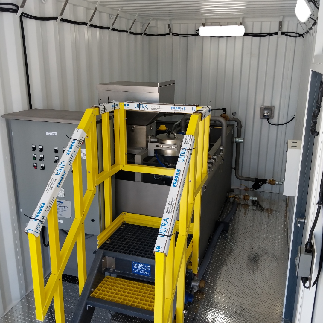 A dry chemical preparation system with yellow stairs inside a small shipping container.