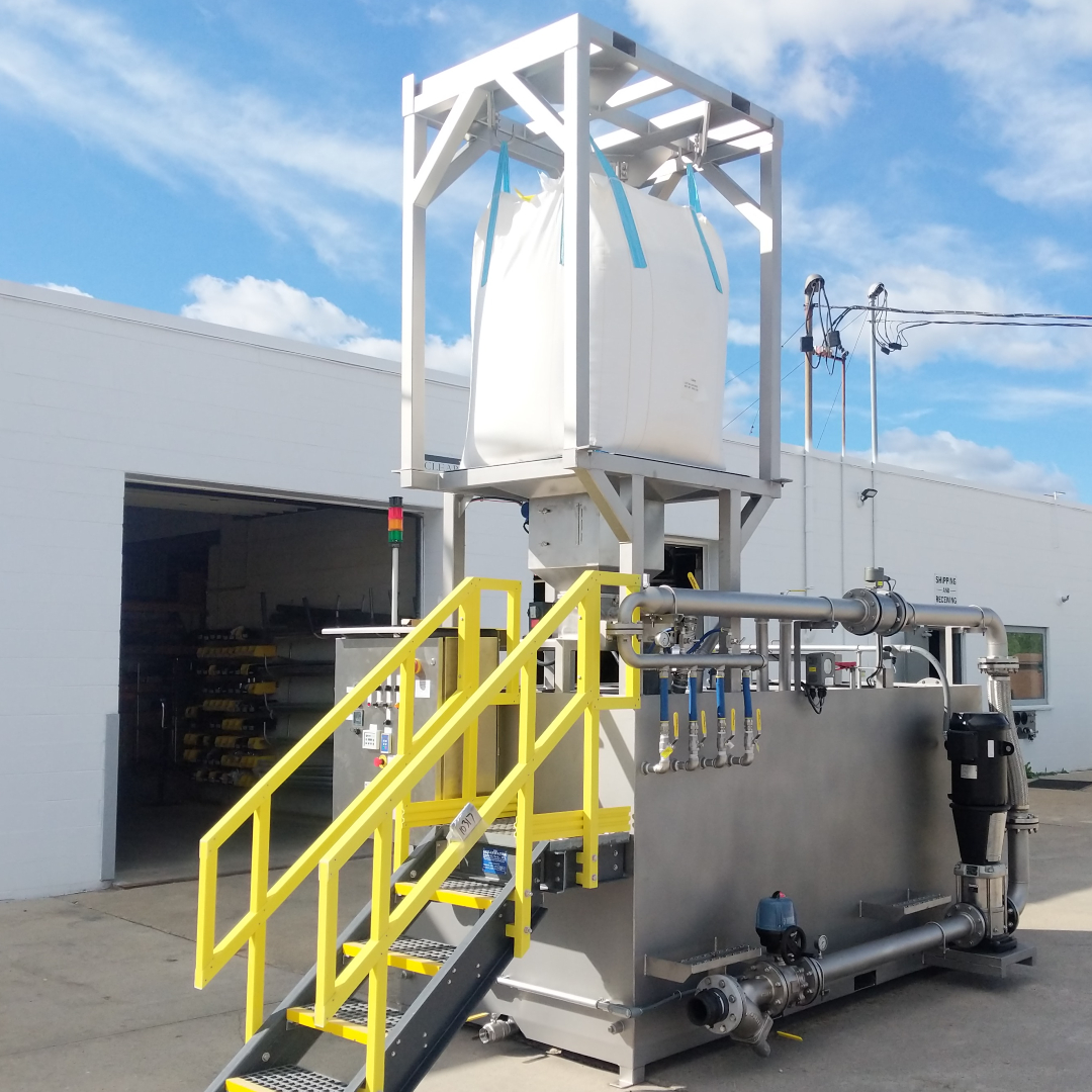 A dry chemical preparation system outside with a square tank, stainless steel piping, and a big white chemical bag.