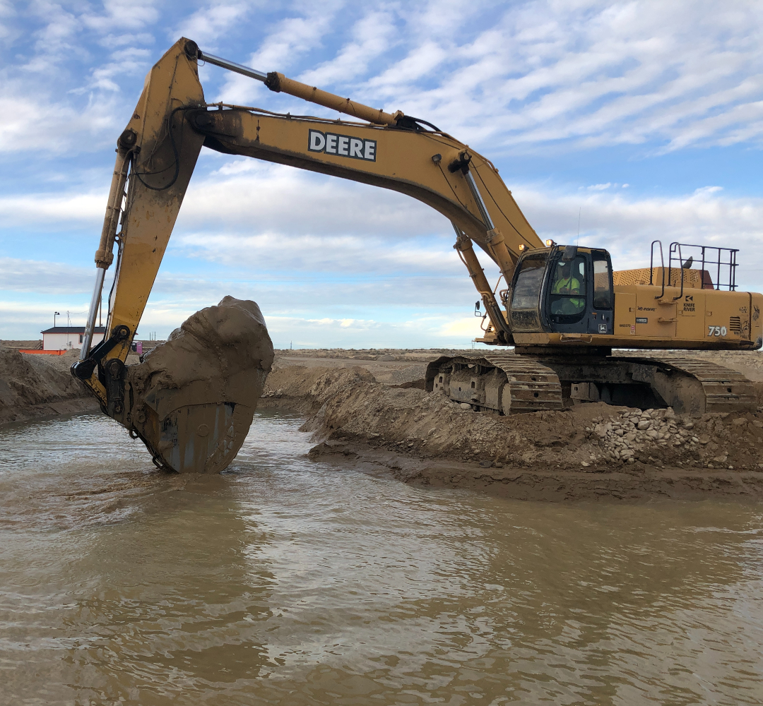 Excavator Bucket out of Pond 3 A yellow excavator with a bucket full of mud from a settling pond.