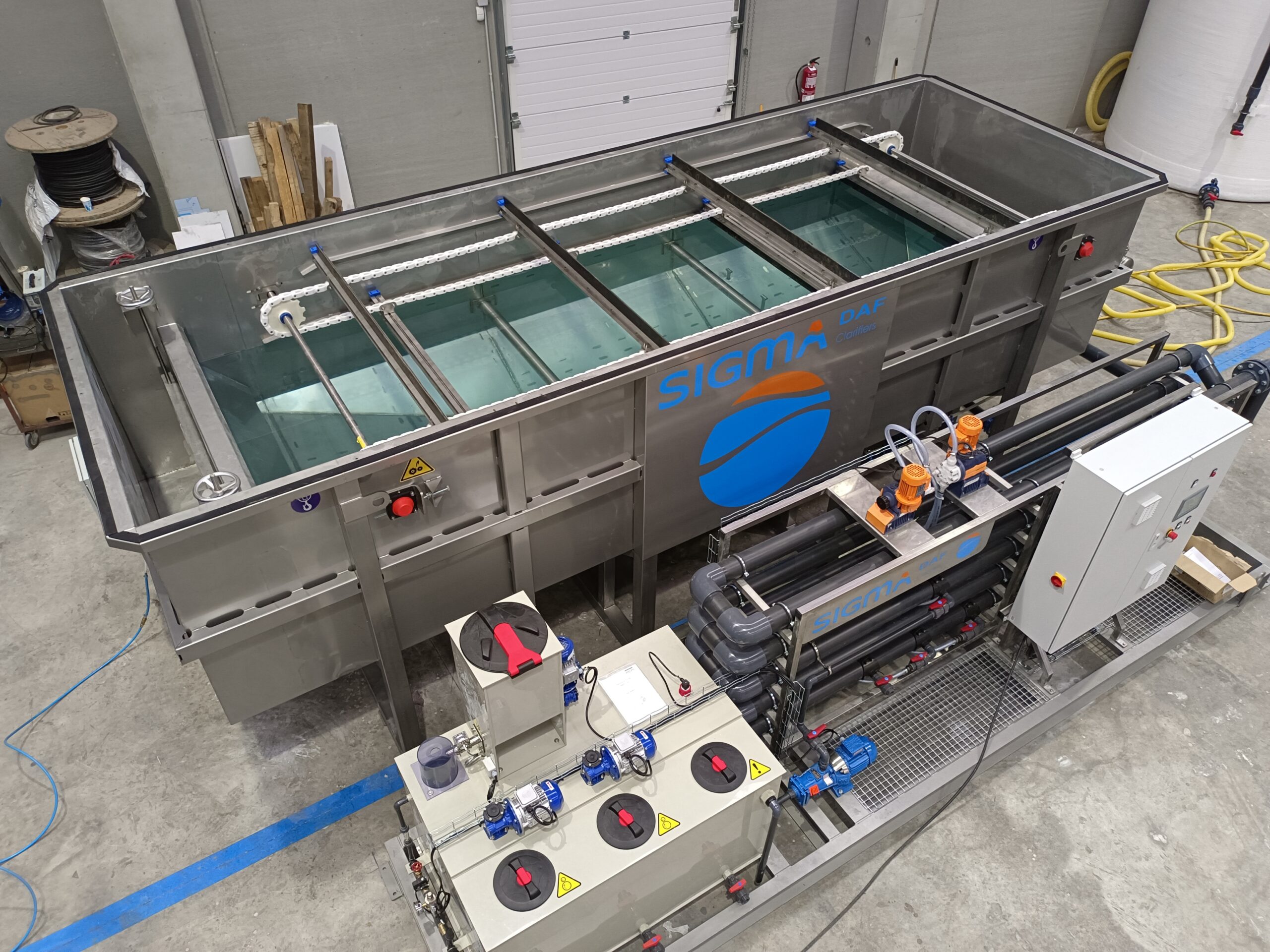 FPAC 30 Compact 1 A DAF clarifier filled with water next to a skid with PVC pipes and other mechanical equipment.