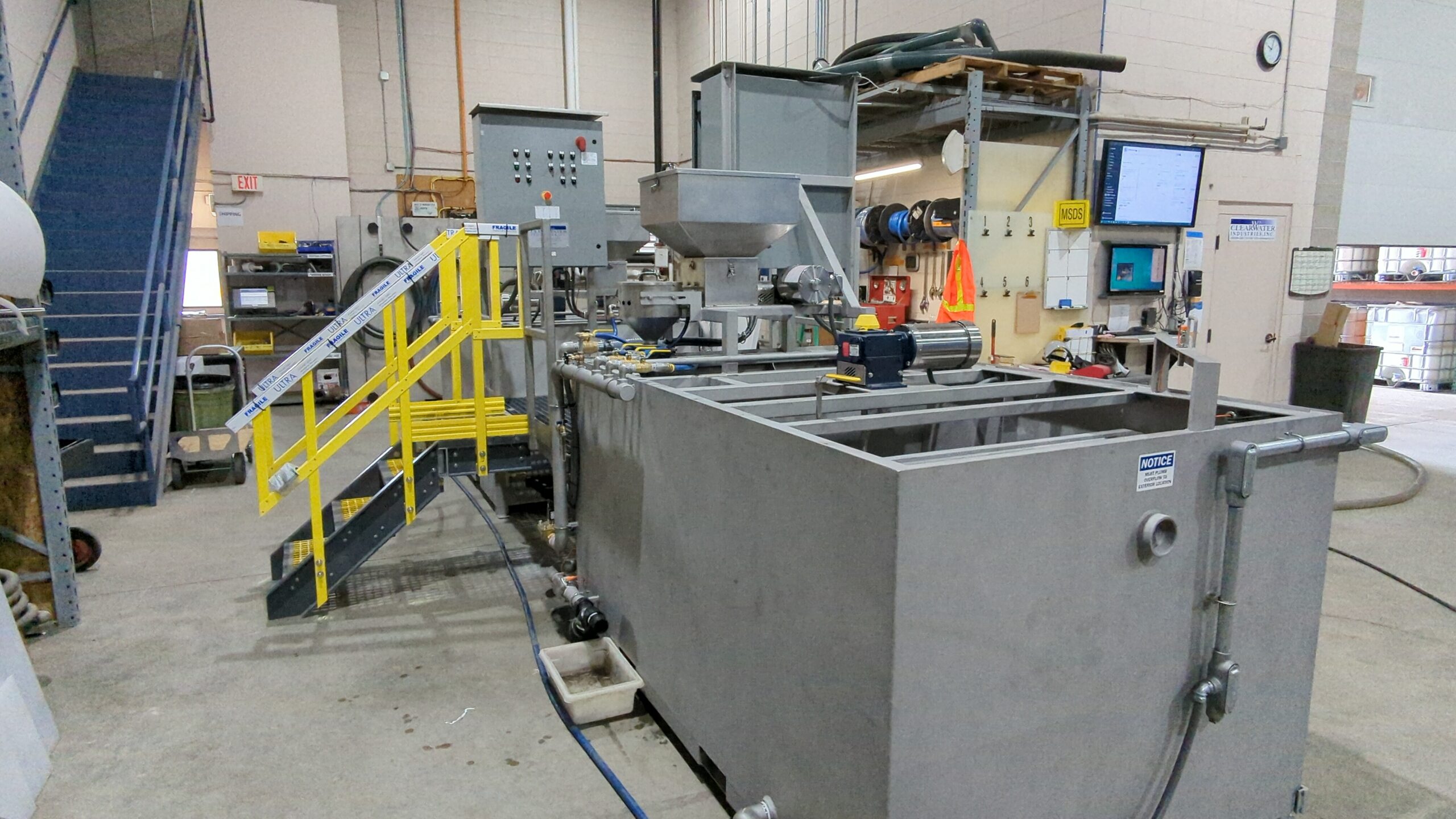 M500SS 2 A closer view of rectangular stainless steel tanks with a yellow painted staircase leading up to control panels.